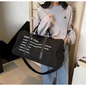 Close-up of black canvas travel bag with white quote print and leather handles