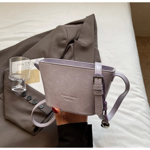 Détail du sac seau violet clair avec texture cuir froissé et pendentif coeur
