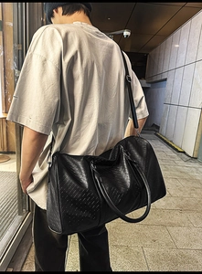 Close-up of black PU leather travel bag with premium woven texture and adjustable strap