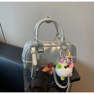 Detail of silver metallic Boston bag with furry charm held in a lifestyle setting