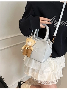 Women's light blue textured shoulder bag with brown plush bear charm and embossed text