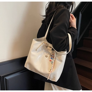 Macro shot of smooth cream leather tote texture with gold logo and stylish charm detail
