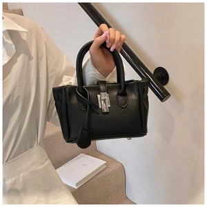 Detail of black lychee grain leather mini bucket bag with silver lock and double handles