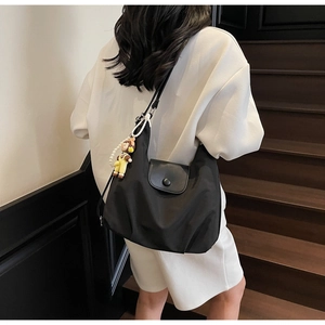 Detail of minimalist black hobo tote bag with a cute pearl charm on a female model