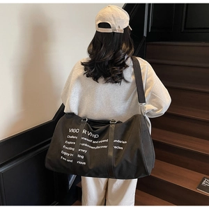 Close-up of a large black canvas travel tote bag with Vigor Vivid text on stairs