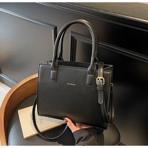 Detailed close-up of a matte black leather handbag with gold SOLAR & MISS logo and straps