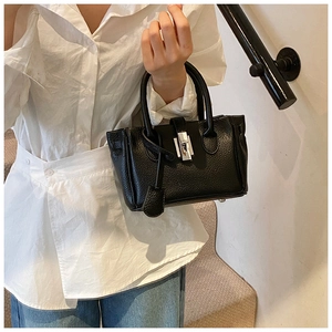 Detail showing high-quality black litchi grain leather and silver metal twist-lock on bag