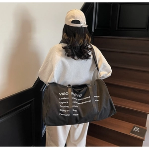 Detailed view of black canvas travel bag with white graphic text on a person's shoulder