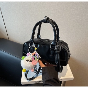 Detail of a black glossy bowling bag with a soft white plush ball and heart charm