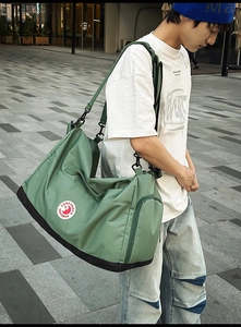 Detail of olive green nylon tote bag featuring side zipper pocket and urban branding