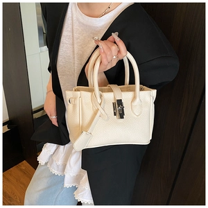 Close-up of cream textured leather handbag with metallic turn-lock and double handles