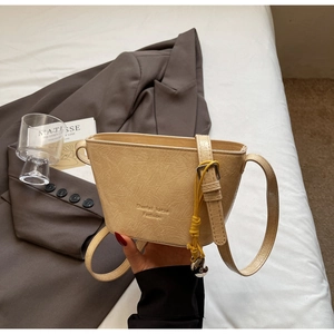 Détail du sac seau crème avec texture plissée et bandoulière élégante