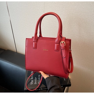 Macro shot of red leather handbag with gold logo and metallic hardware detail