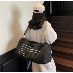 Detail shot of the black large canvas duffel bag with stylish white slogan printing