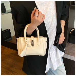 Close-up of litchi texture leather handbag with silver rotary lock and dual handles