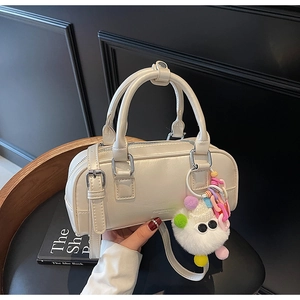 Detail view of cream white patent mini bowling bag with cute plush pendant and strap