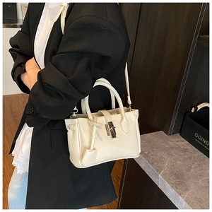 Detail of off-white lychee grain leather handbag with silver twist-lock and shoulder strap