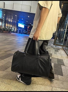 Close-up of the black woven texture and sturdy leather handle of the large travel tote bag