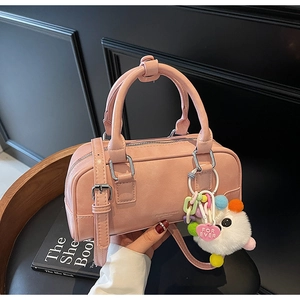Detailed view of pale pink bowling bag with plush pompom and heart charm accessory
