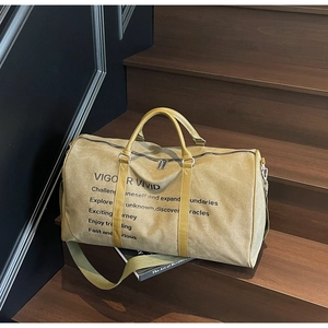 Detail of khakhi canvas travel bag with 'VIGOR VIVID' print on wooden stairs