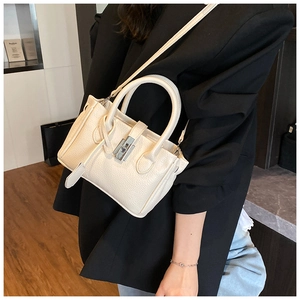Chic beige bucket bag with silver turn-lock clasp shown worn as a crossbody by model