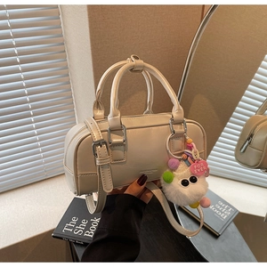 Detail of cream leather bowling bag with silver zipper and white plush monster charm