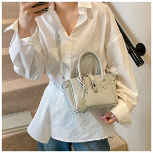 Detail of lychee pattern leather bucket bag with rotating lock and shoulder strap on model