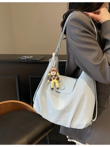 Light blue crescent canvas tote bag with a cute doll pendant shown on a model