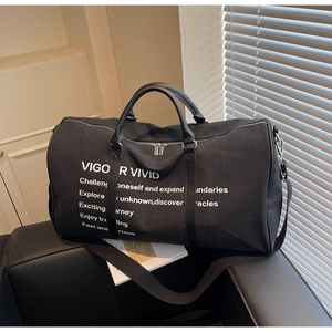 Detail of black canvas travel bag with VIGOR VIVID print on a leather sofa