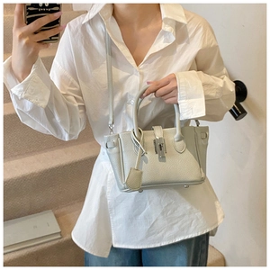 Detail of light gray lychee grain leather bucket bag with metal twist lock and strap