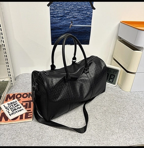 Close-up of black PU travel bag featuring woven texture detail and metal buckles
