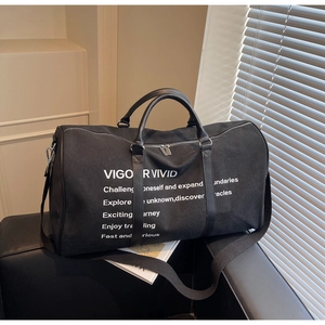 Detail shot of black canvas duffel bag with VIGOR VIVID typography and dual leather handles