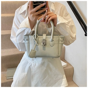 Detail of mint green textured leather handbag with silver lock and cylindrical handles