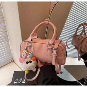 Detail of pink bowling bag featuring a plush monster charm and soft textured faux leather