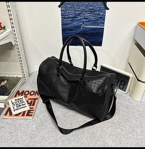 Close-up of black PU travel bag showing embossed houndstooth texture and top handle
