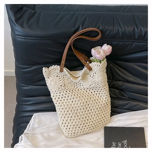 Detail of hand-woven cream tote bag with brown leather handles and gold rivets