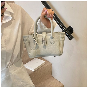 Detailed view of cream-colored pebble leather texture and metallic turn-lock closure on mini bag