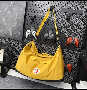 Detail of a yellow nylon tote bag with brand logo hanging on a dark pegboard wall