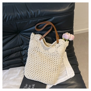 Close-up of crochet hollow weave pattern and brown leather strap on cream shoulder bag