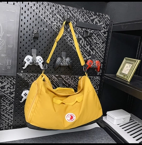 Detail of a bright yellow nylon tote bag with black base hanging on a pegboard