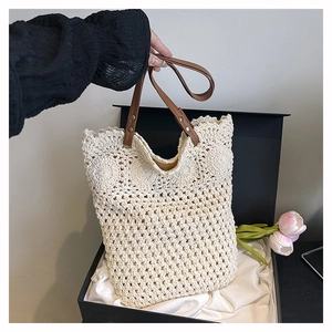 Detailed macro view of cream crochet tote bag with dark brown leather handle and metal rivets