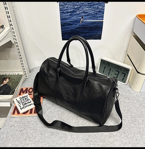 Close-up of black crocodile embossed tote bag with thick handles and adjustable strap