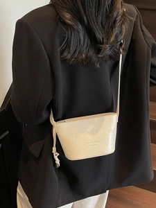 Sac seau blanc cassé minimaliste avec texture plissée porté en sac à bandoulière chic