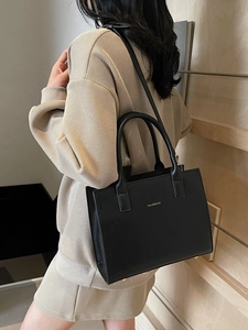 Elegant black faux leather tote bag with gold logo and adjustable shoulder strap for women