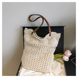 Detail of woven beach tote bag with beige hollow knit pattern and brown leather handle