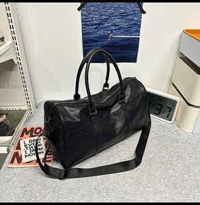 Detail of black crocodile texture travel tote bag with handles and nylon shoulder strap