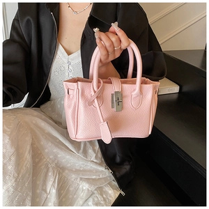Detail of light pink pebble leather bucket bag with silver clasp lock and top handles