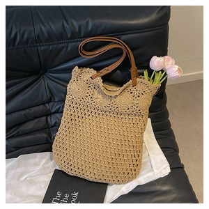 Detail of woven beach tote showing brown leather handles and scalloped crochet edges