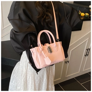 Detail of pink lychee leather handbag featuring metal turn-lock and detachable strap