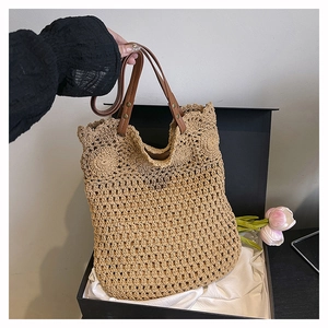 Detail of woven straw shoulder bag with hollow mesh pattern and brown leather handles